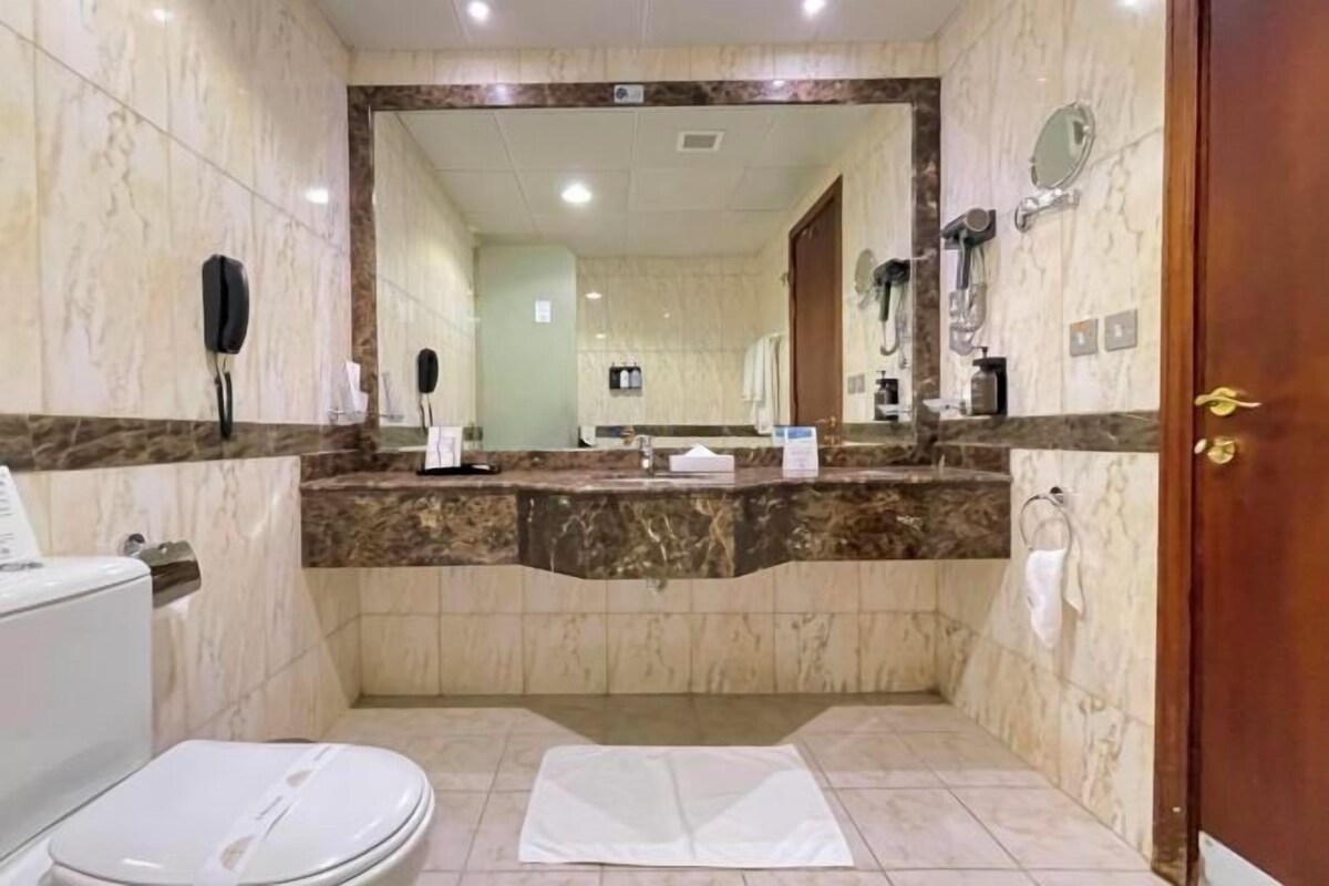 Een badkamer met toilet, wastafel en spiegel.