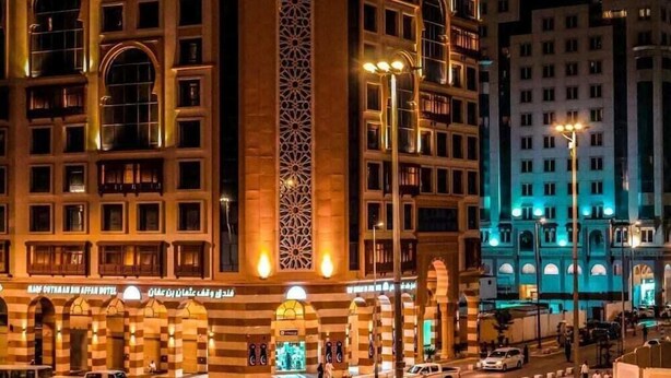 A hotel with a prominent arched entrance and a vertical decorative column. - Waqf Othman Bin Affan Hotel (Madinah)
