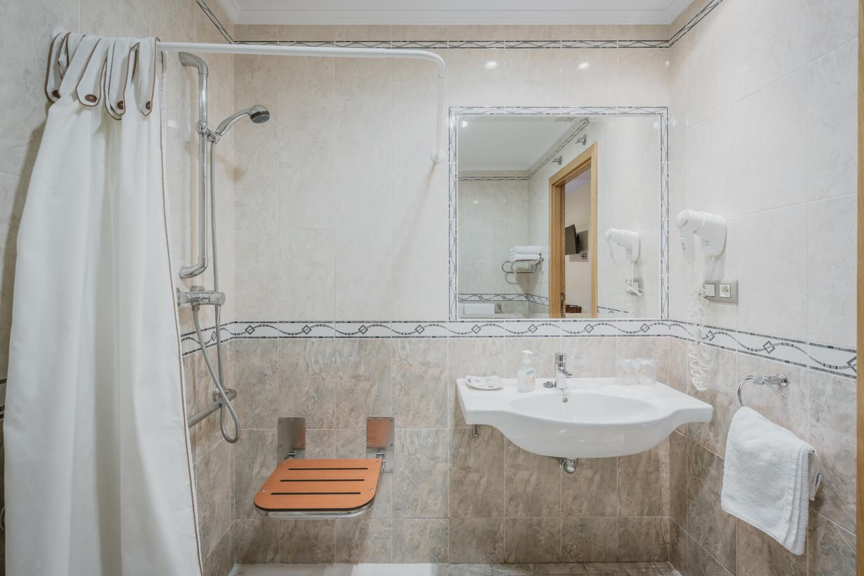 A bathroom with a shower, a sink, a mirror, and a towel rack.
