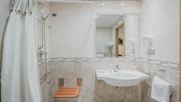 A bathroom with a shower, a sink, a mirror, and a towel rack.