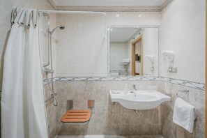 Un baño con ducha, lavamanos, espejo y toallero.