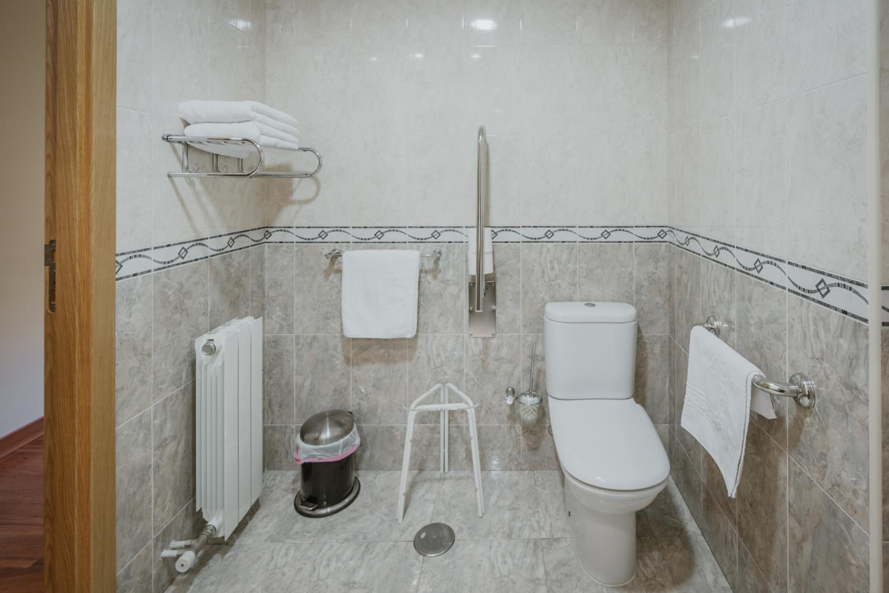 Un baño con inodoro, bidé, toallero y radiador.