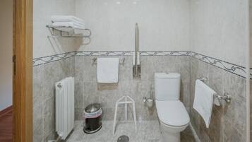 Un baño con inodoro, bidé, toallero y radiador.