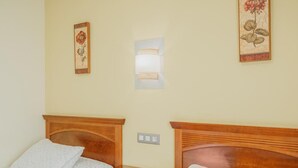 Hotelkamer met twee bedden, een nachtkastje, een wandlamp en twee florale kunstwerken in lijsten.