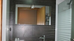 Un baño con lavamanos, espejo y ducha.