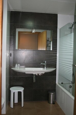 Un baño con lavamanos, espejo y ducha.