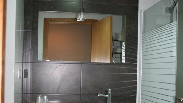Un baño con lavamanos, espejo y ducha.
