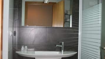 A bathroom with a sink, mirror, and shower.
