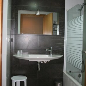 Une salle de bain avec un lavabo blanc, un miroir et un espace douche.
