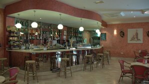 Un área de bar con un mostrador curvo, varios taburetes y una variedad de botellas en estanterías.