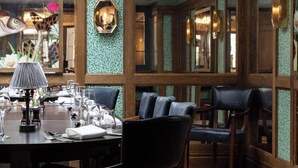 Un coin repas avec une table ronde dressée pour quatre personnes, entourée de chaises rembourrées.