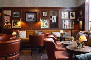 A lounge area with leather armchairs, a sofa, and a coffee table, decorated with framed pictures and small plants. - The White Hart Hotel Lincoln (Lincoln)
