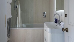 A modern bathroom with a glass-enclosed shower, a standalone bathtub, and a vanity with a mirror. - The White Hart Hotel Lincoln (Lincoln)