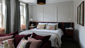 A hotel room with a large bed, two bedside tables, a hanging light fixture, and a view of the city. - The White Hart Hotel Lincoln (Lincoln)