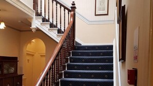 Eine Treppe mit dunklem Teppich und Holzhandläufen.