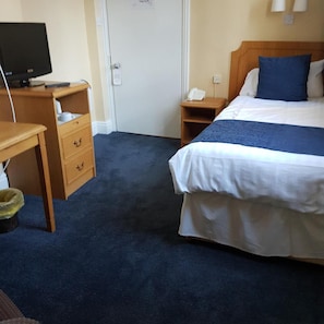 A hotel room with a bed, a desk, a chair, a television, and a telephone. - The Hand Hotel (Llangollen)