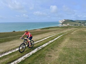 A cyclist on a grassy path with a coastal view. - Calverts Hotel - Newport Isle of Wight (Newport)