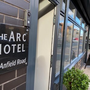 A hotel sign with 'The ARC Hotel' and 'Anfield Road' on a brick wall. - The Arc Hotel (Liverpool)