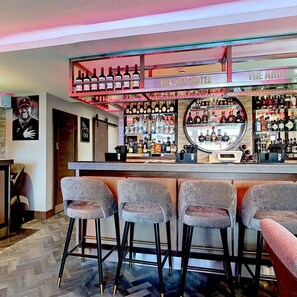 A bar area with a counter, stools, and shelves of bottles. - The Arc Hotel (Liverpool)