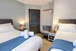 A hotel room with two beds, a chair, a nightstand, and a wall-mounted heater. - The Arc Hotel (Liverpool)