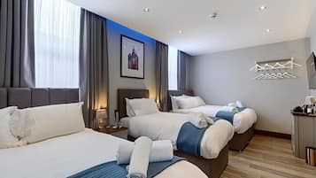 Quarto de hotel com duas camas, uma janela grande com cortinas, uma obra de arte na parede e um porta-roupas.