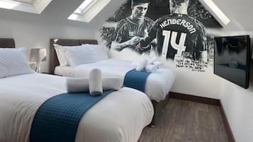 Quarto de hotel com duas camas, um pôster grande de um atleta, claraboias e uma fotografia emoldurada na parede.