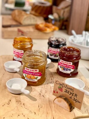 Presentatie van BEYER Confiture Extra potten op een houten tafel, met kleine lepeltjes en een bordje met de prijs.