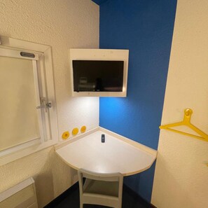 Una habitación pequeña con una mesa blanca, un armario blanco, una pared azul y un perchero amarillo.