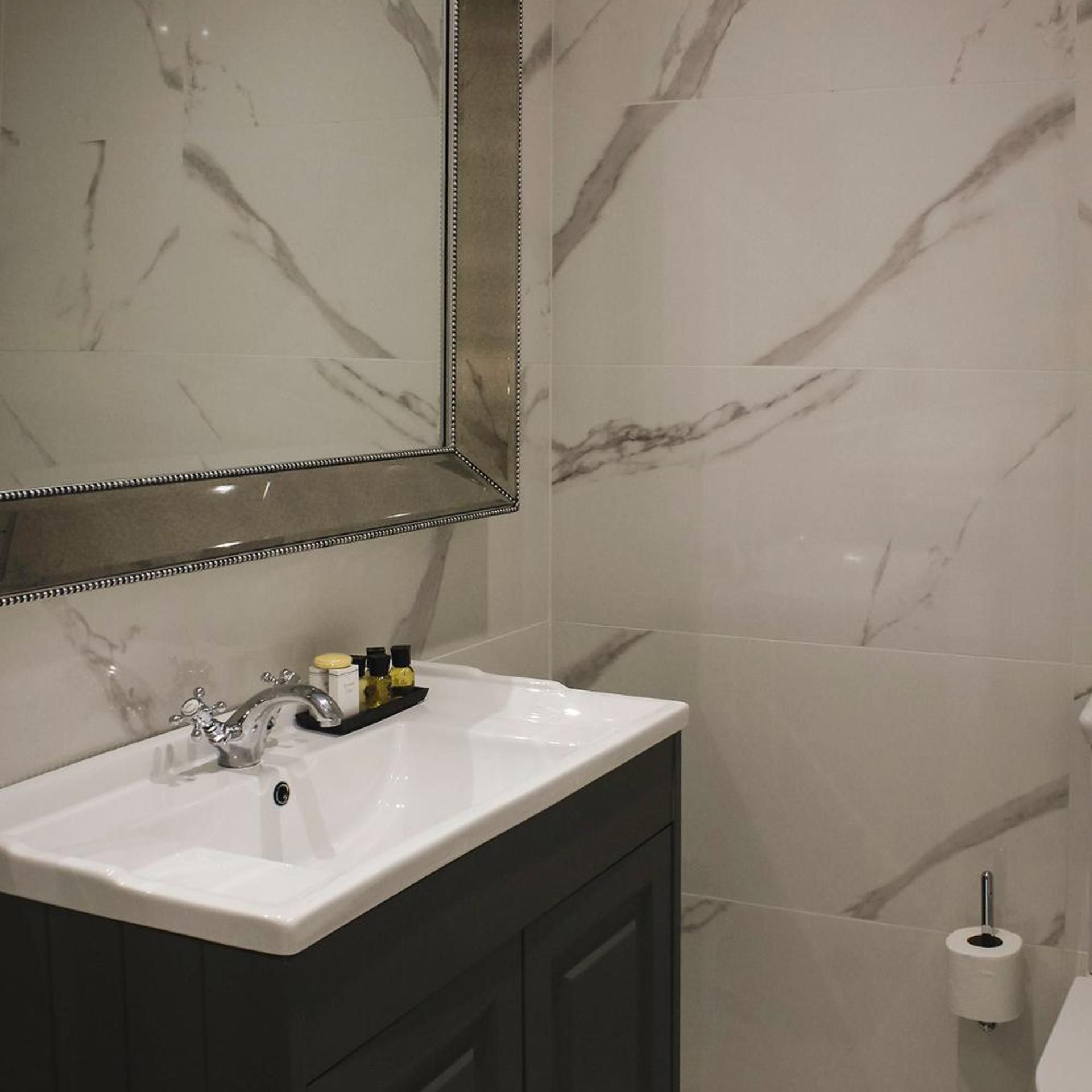 A bathroom with a white sink, a mirror, and a toilet.