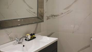 A bathroom with a white sink, a mirror, and a toilet.