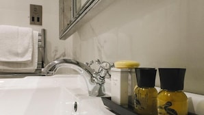 Une salle de bain avec un lavabo blanc, un robinet chromé, un miroir, un porte-serviettes et deux bouteilles de gel douche de la marque Duck Island.