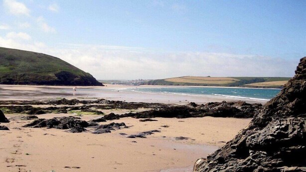 A beach with rocky areas, a sandy shore, and distant hills. - The Bodmin Jail Hotel (Bodmin)