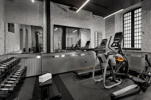 Un gimnasio con equipo de ejercicio, un espejo grande y una ventana que deja entrar luz natural.