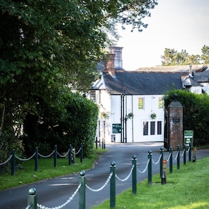 A traditional building with a white facade, a brick chimney, and a sign indicating a hotel reception and car park. - Manor Parc Hotel (Cardiff)