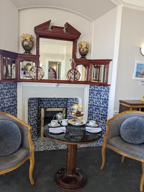 Una habitación con chimenea, una mesa con servicio de té y dos sillas.