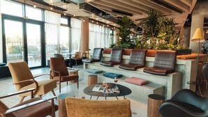 A modern lounge area with leather seating, a coffee table, and a large window offering a view of the outdoors.