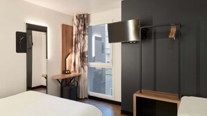 A modern hotel room with a large bed, a desk, a chair, a TV, and a window with curtains. - B&B Hotel Le Port Marly Saint Germain en Laye (La Haute-Maison)