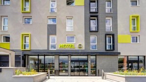 A modern hotel with a prominent 'HOTEL' sign, large windows, and a brick facade. - B&B Hotel Le Port Marly Saint Germain en Laye (La Haute-Maison)