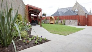 A courtyard with a covered seating area, a stone building with a pitched roof, and a well-maintained lawn. - Palace Hotel (Peterhead)