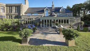 A large stone building with a covered patio area, multiple windows, and a well-maintained garden. - Lanelay Hall Hotel and Spa (Pontyclun)