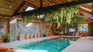 An indoor swimming pool with stone walls, wooden beams, and hanging plants. - Lanelay Hall Hotel and Spa (Pontyclun)