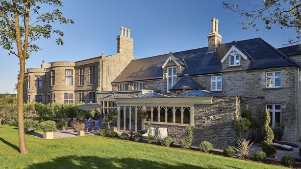 A large stone building with multiple chimneys, a covered patio area, and a well-maintained garden. - Lanelay Hall Hotel and Spa (Pontyclun)