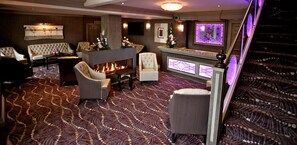 A hotel lobby with a fireplace, seating area, and a bar. - Greenvale Hotel (Cookstown)