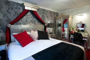 A hotel room with a large bed, a wardrobe, a mirror, and a desk with a chair. - Greenvale Hotel (Cookstown)