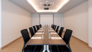 Ein Konferenzraum mit einem langen Tisch, schwarzen Stühlen und einem Projektor.