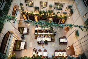 An indoor courtyard with multiple seating areas, hanging lights, and potted plants. - Palacio Ludovice (Lisbon)