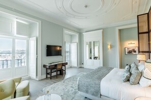 Une chambre spacieuse avec un grand lit, un bureau avec une chaise, une télévision et une vue dégagée grâce à de grandes fenêtres.
