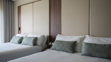 Una habitación de hotel con dos camas, un cabecero de madera y una mesita de noche con una lámpara.