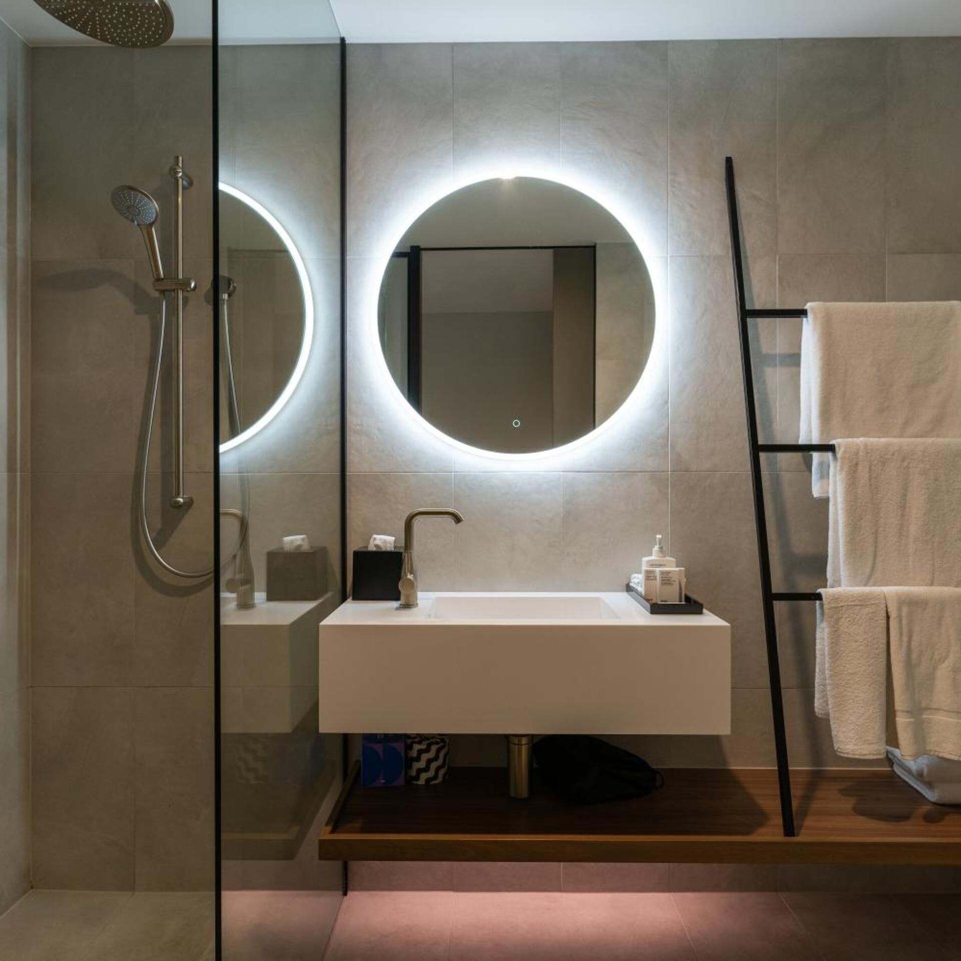 A modern bathroom with a round mirror, a sink, and a shower.
