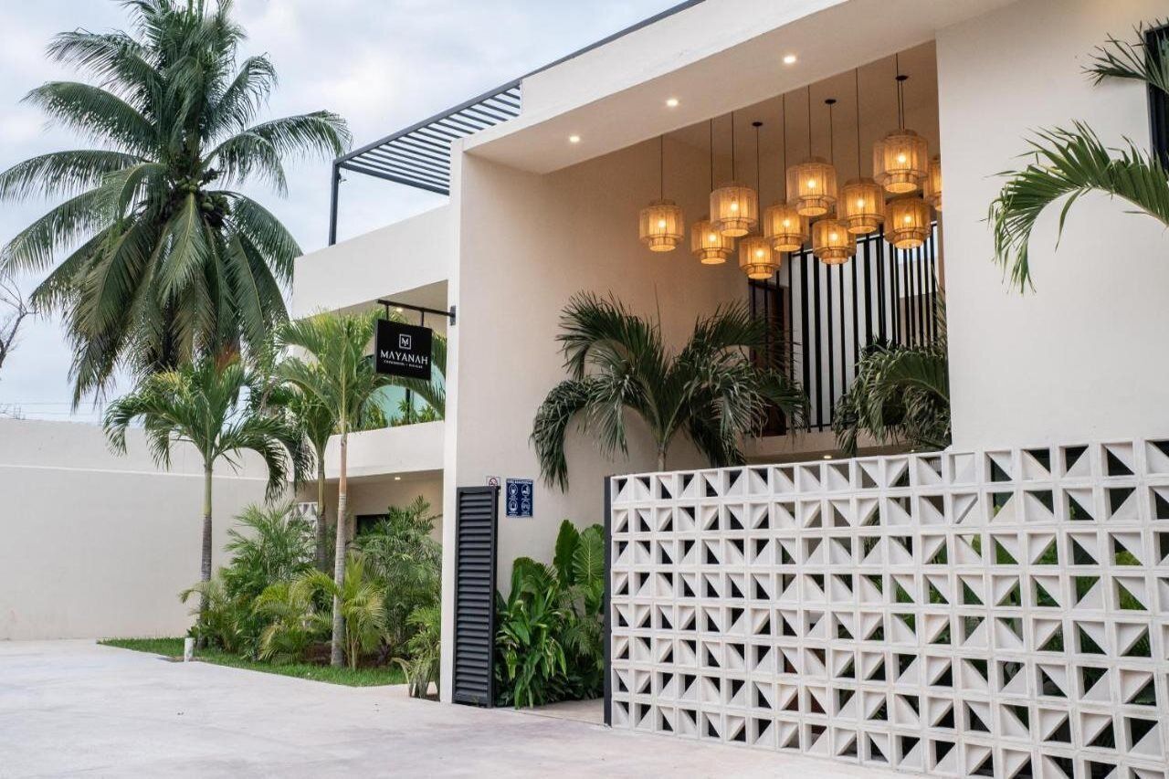 Un edificio moderno con fachada blanca, palmeras y una cerca geométrica blanca.
